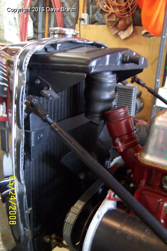 Removing old upper hose 3.jpg - Removing the old upper radiator hose. Notice the radiator stays are detatched, and the radiator and grille are able to safely rock forward on the mounts. The hose eases off relatively well in this position. On installation, starting the clamps on the slightly thicker hose was a different matter!