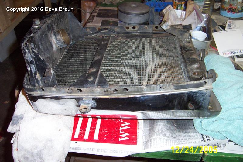 rad and shell face down RHS.JPG - The radiator with the mounting flange, ears and shell. Notice the buffer strip is intermittent. It laces through the holes, and when it gets old, it can crack and break at those points.