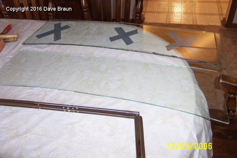 Old and new windscreen glass.jpg - Comparing the old glass to the new. The old glass has the 'x's' on it. Harmon Glass ordered a 12"x42" sheet and cut the new one to match the old. It looks about as close as it could be.