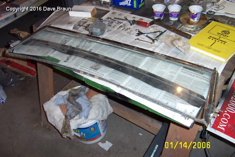 removing glass from bottom.JPG - Removing glass from the bottom. All the scews save one came out. I will have to drill the head off one. The spacers inside the top rail are pot metal, as are the side mount plates. One of the top spacers flew across the garage.